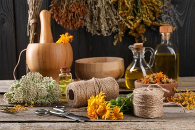 Different herbs and flowers, thread, scissors on wooden table