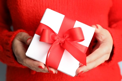 Young woman holding Christmas gift, closeup view