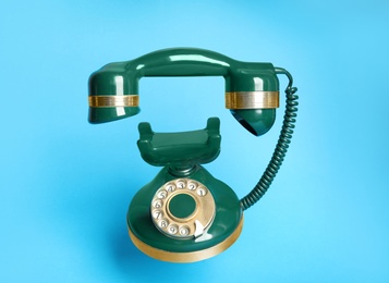 Photo of Green vintage corded phone on light blue background