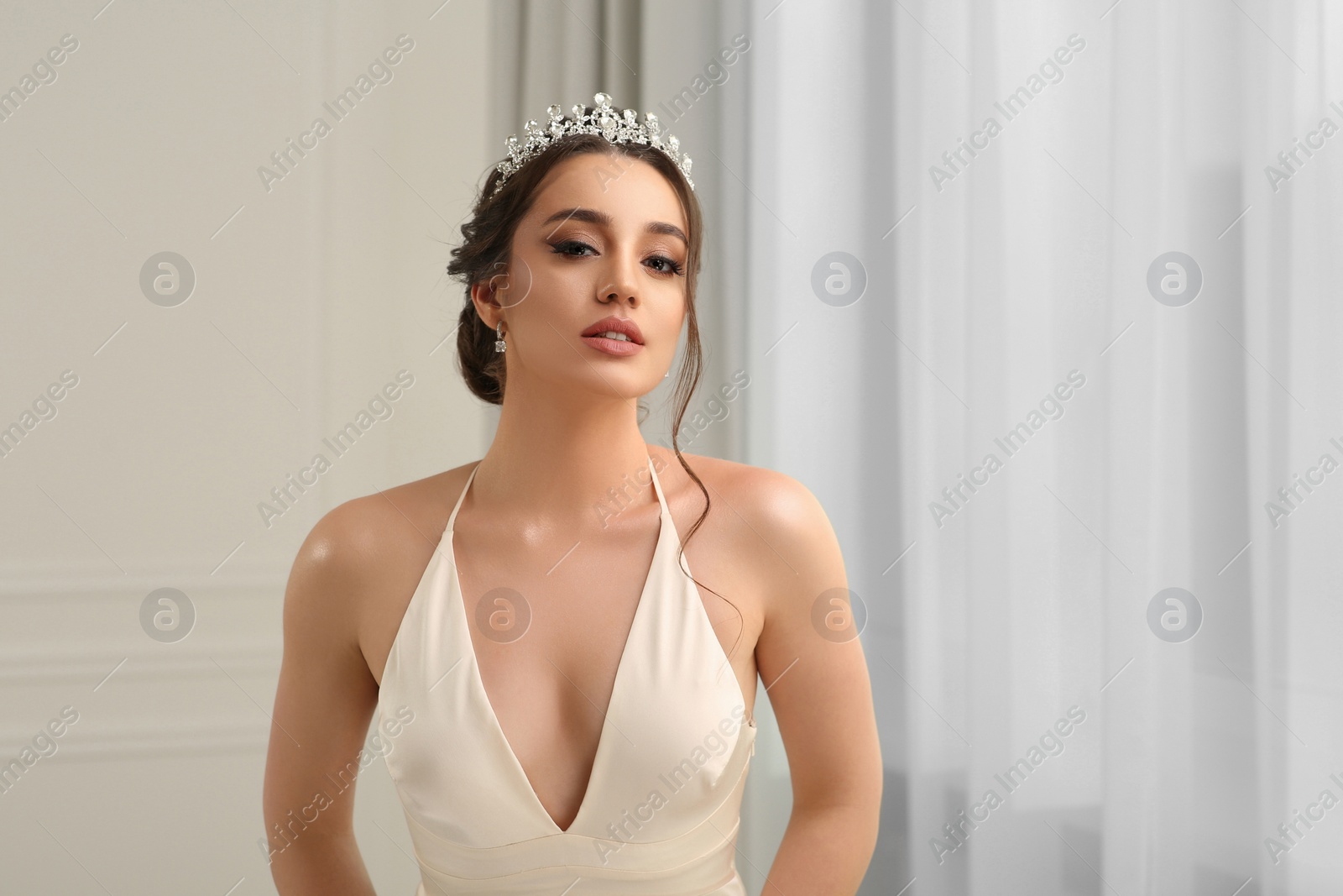 Photo of Beautiful young woman wearing luxurious tiara indoors, space for text