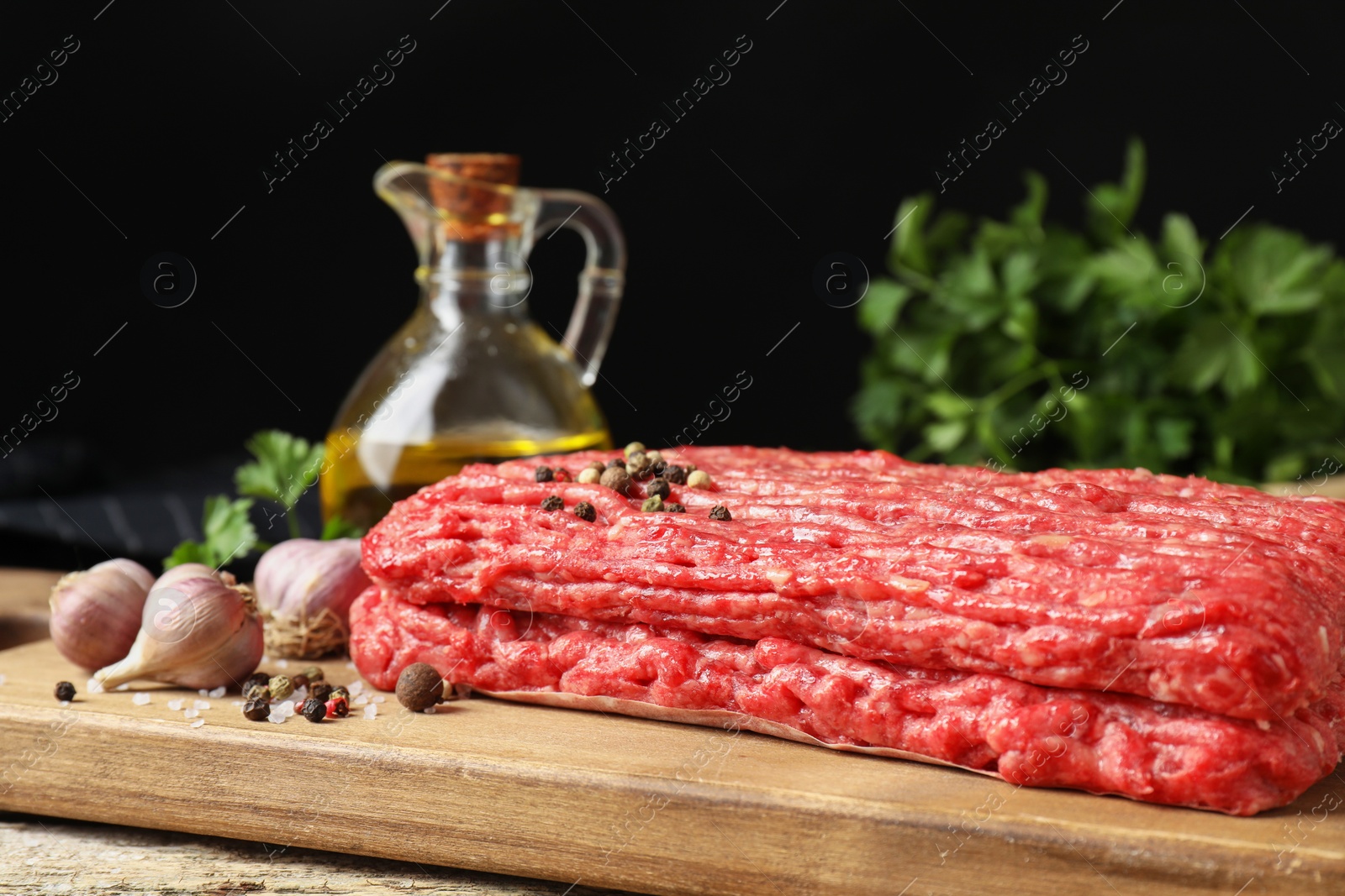 Photo of Raw ground meat, spices, parsley and oil on table, closeup