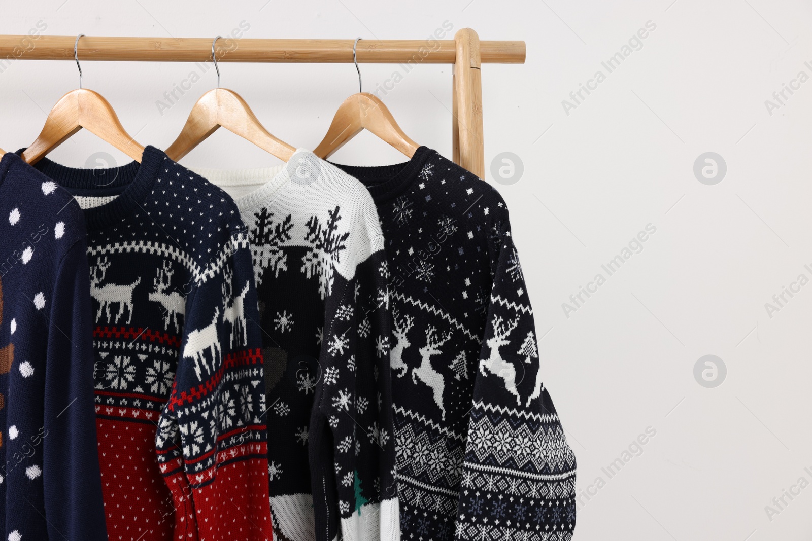 Photo of Rack with different Christmas sweaters on white background, space for text