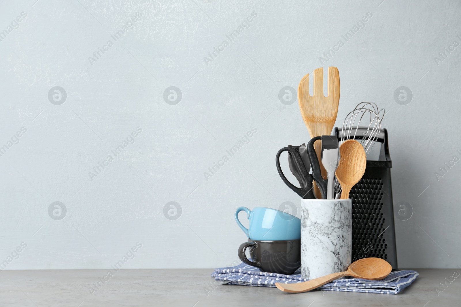 Photo of Different kitchen utensils on table against light background. Space for text