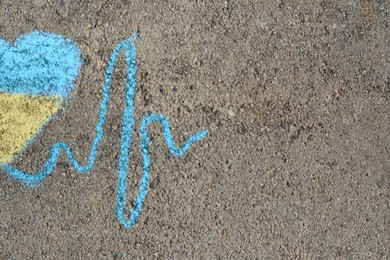 Photo of Cardiogram line with heart drawn by blue and yellow chalk on asphalt, top view. Space for text