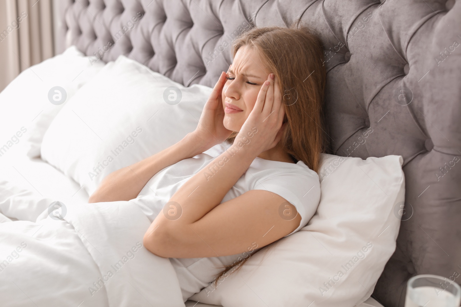 Photo of Young woman with terrible headache lying in bed