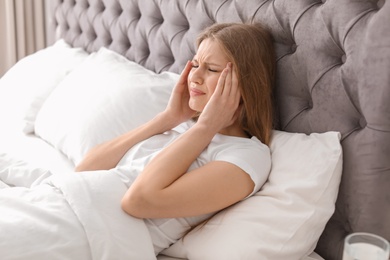 Photo of Young woman with terrible headache lying in bed