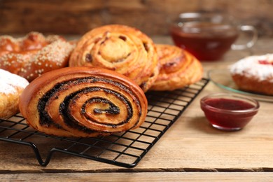 Different tasty freshly baked pastries served with jam on wooden table