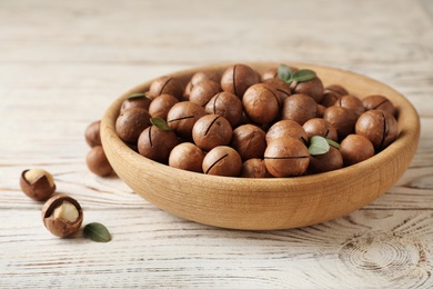Photo of Plate with organic Macadamia nuts on wooden background