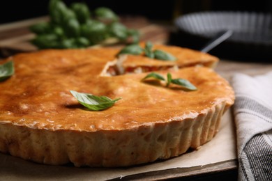 Delicious pie with meat and basil on wooden board, closeup