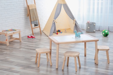 Cozy kids room interior with table, stools and play tent