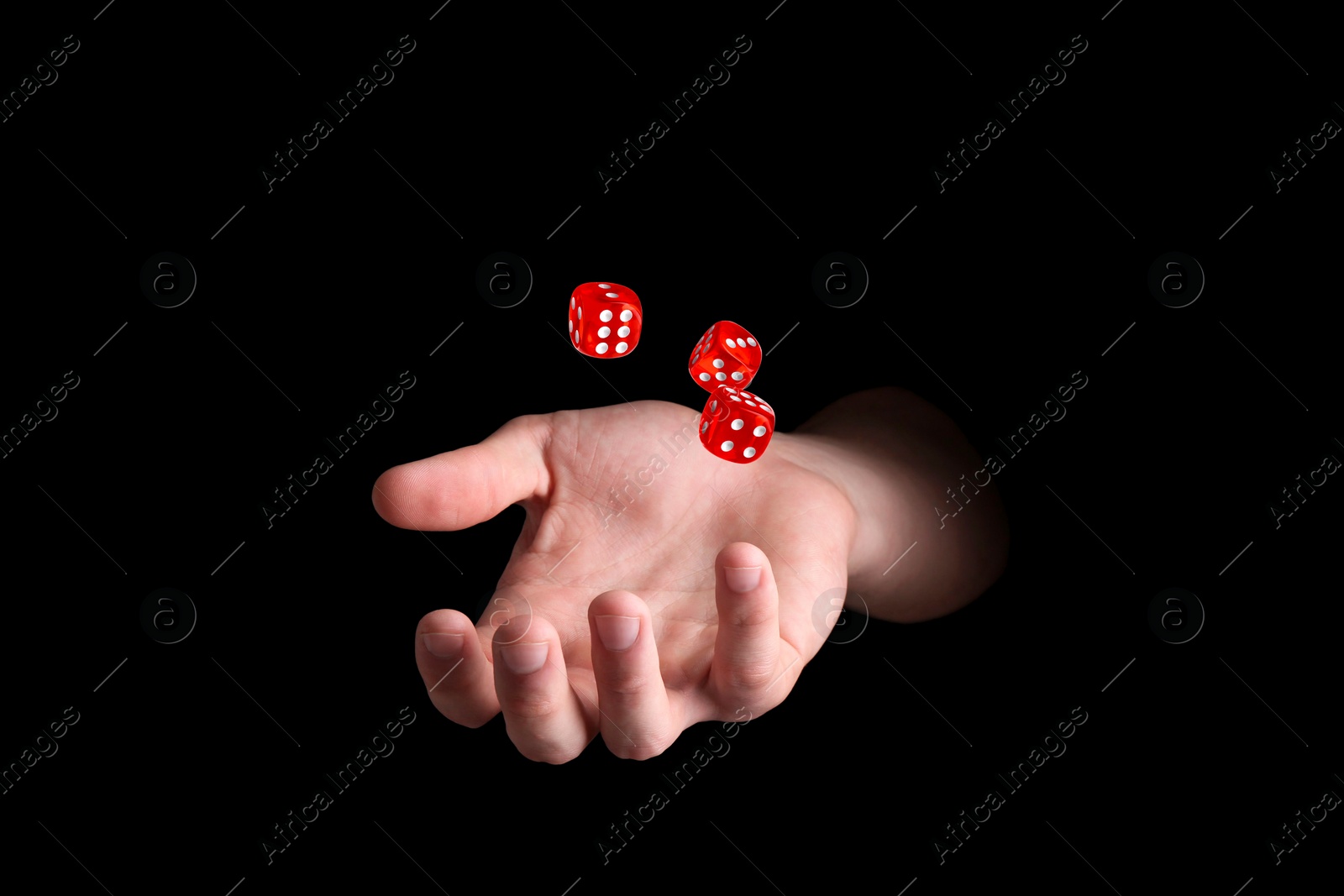 Image of Man throwing red dice on black background, closeup