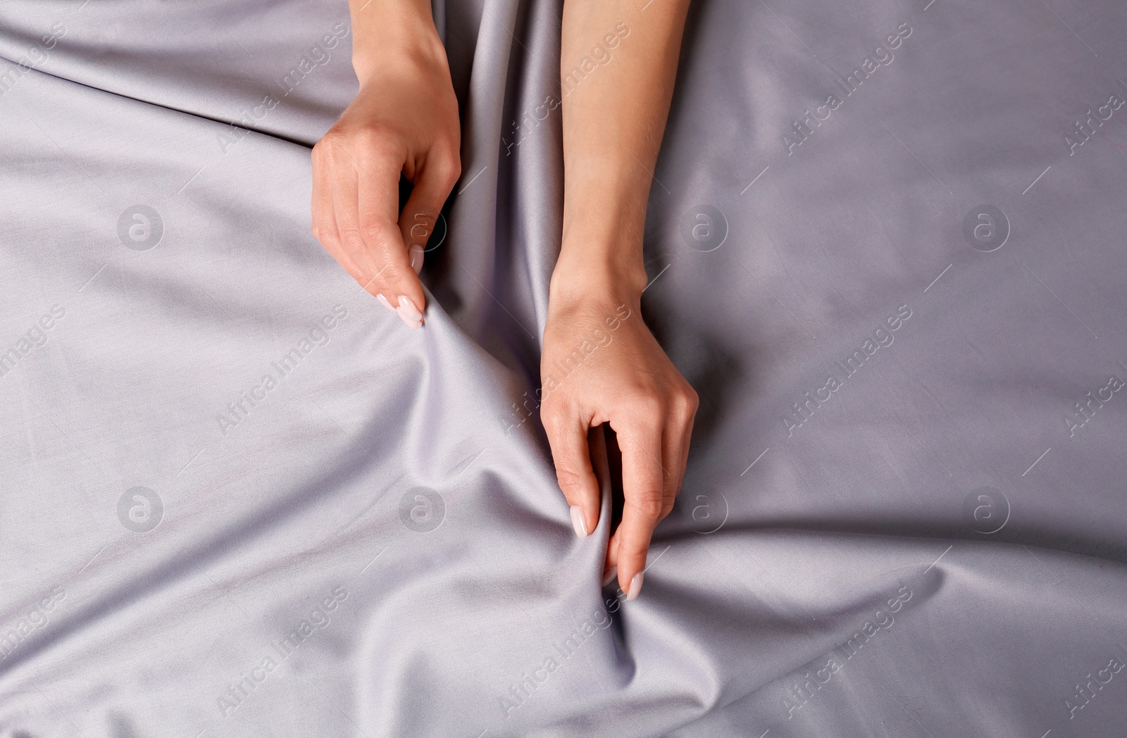 Photo of Woman touching soft silver fabric, top view