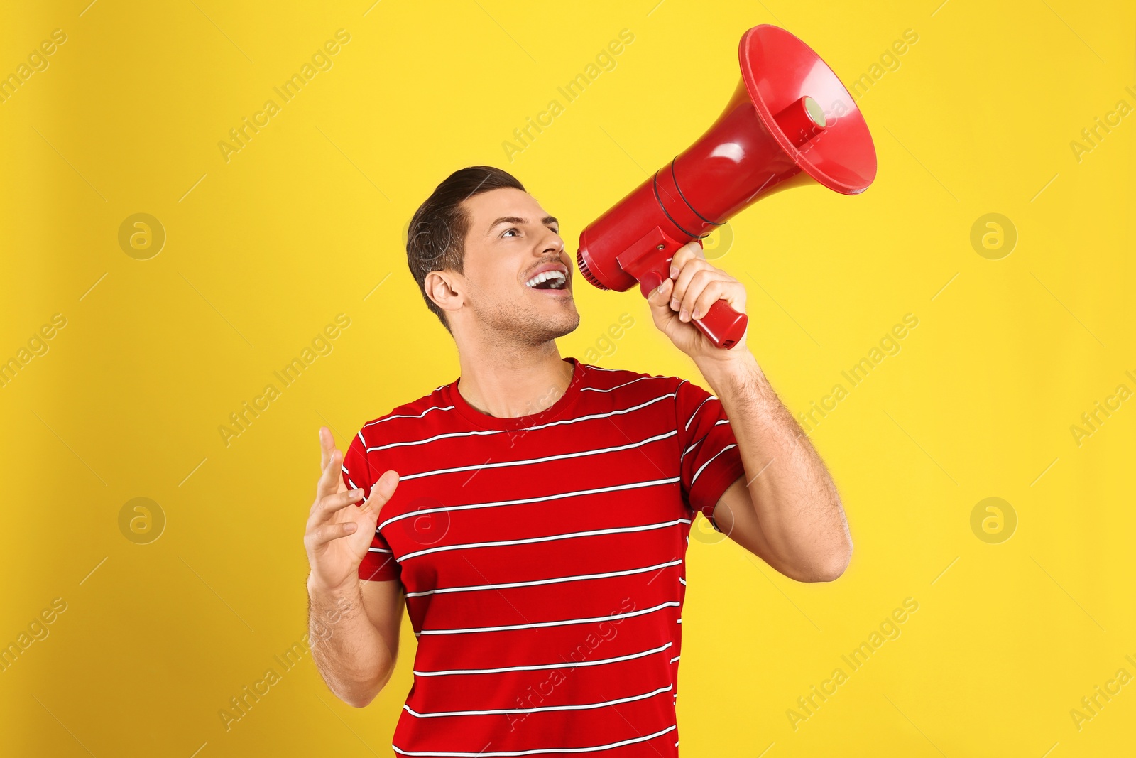 Photo of Handsome man with megaphone on yellow background