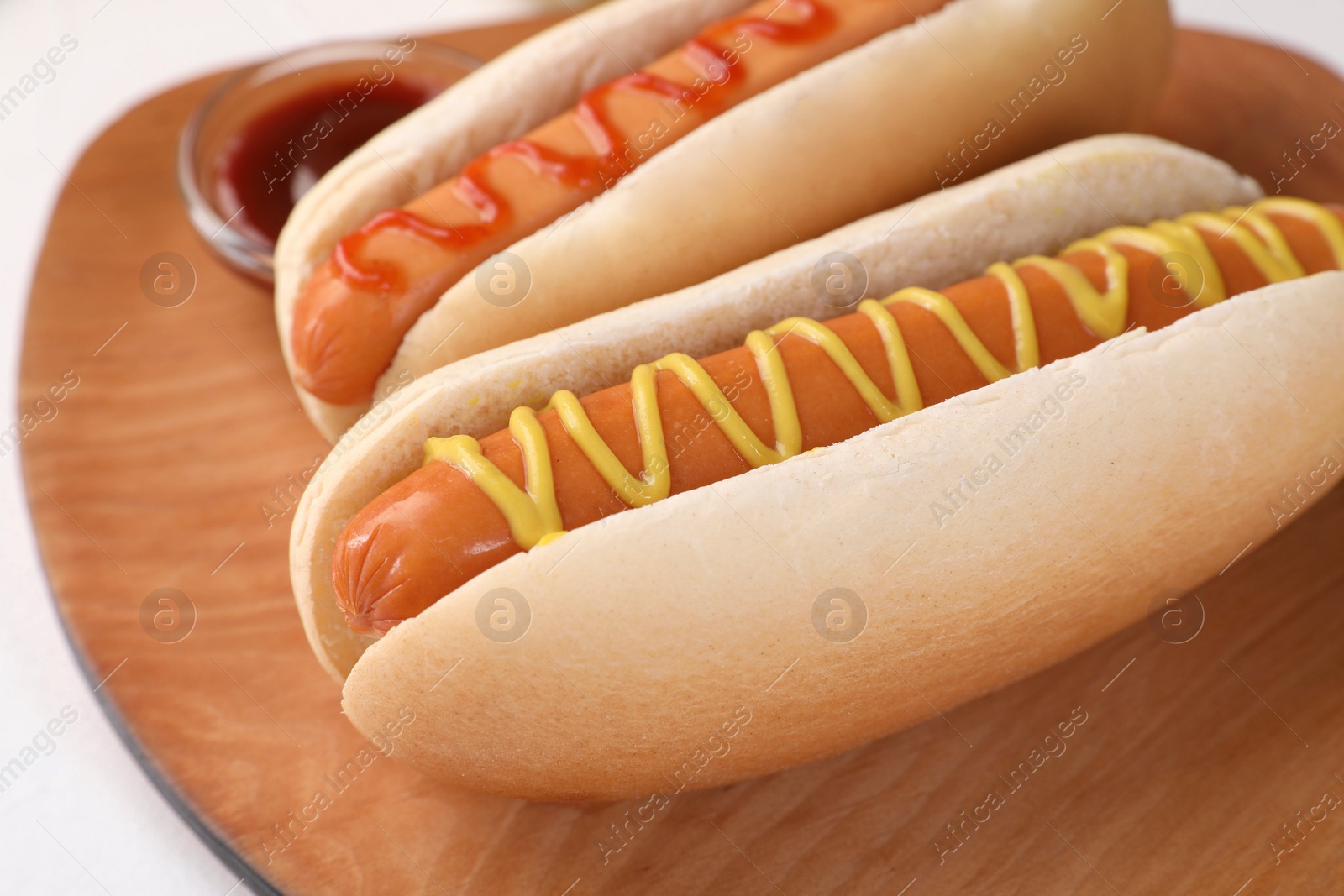 Photo of Tasty hot dogs with ketchup and mustard on white table, closeup