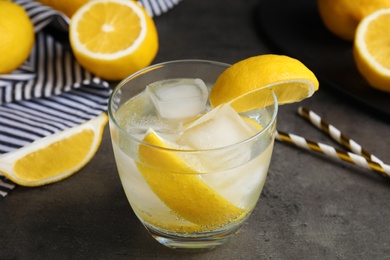 Photo of Soda water with lemon slices and ice cubes on grey table