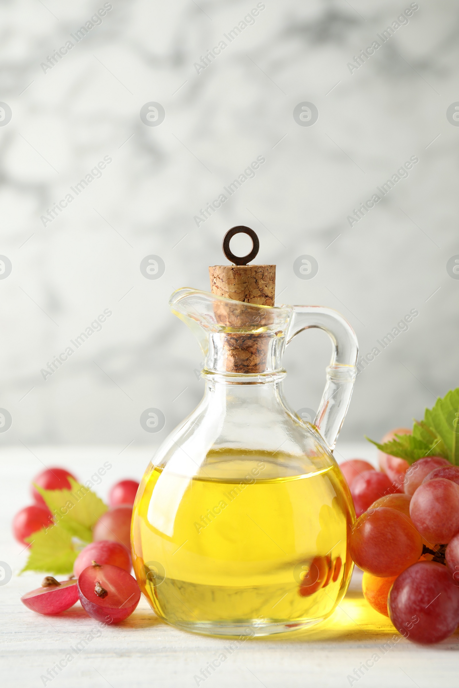 Photo of Natural grape seed oil and fresh berries on white wooden table. Organic cosmetic