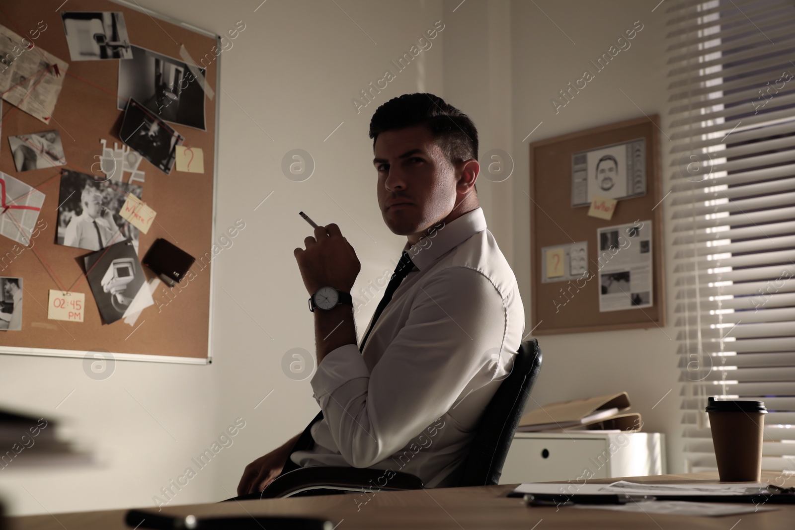 Photo of Professional detective smoking cigarette in his office