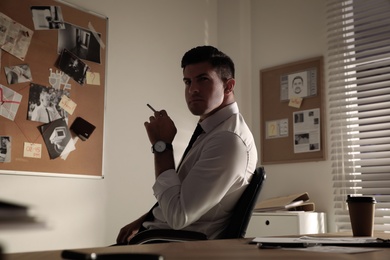 Photo of Professional detective smoking cigarette in his office