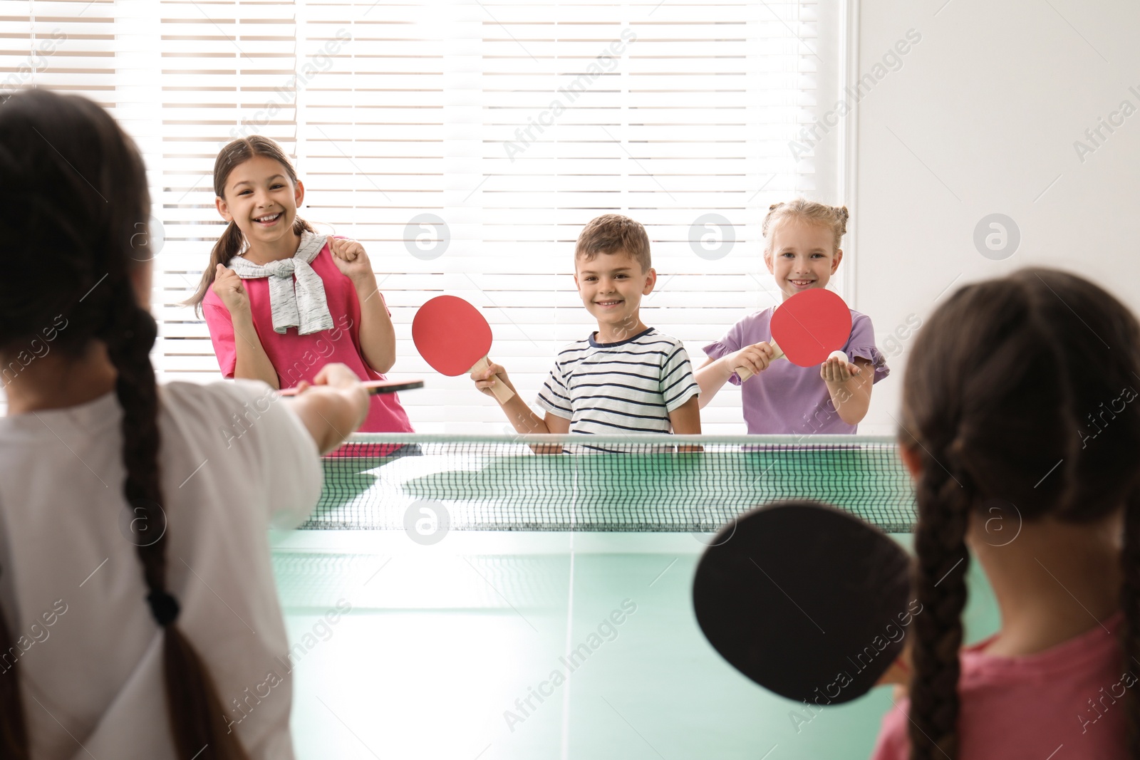 Photo of Cute happy children playing ping pong indoors