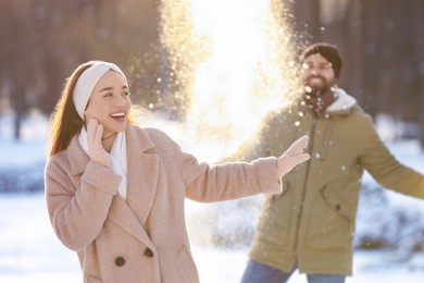 Happy couple playing snowballs on winter day outdoors