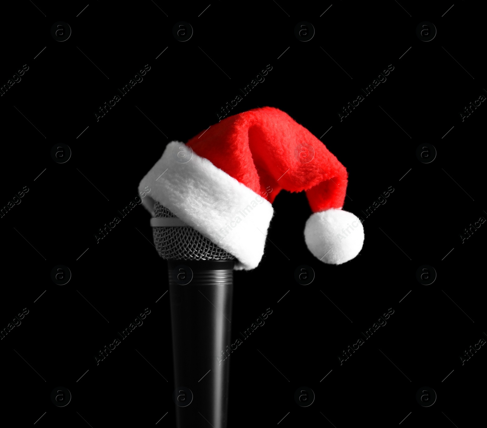 Photo of Microphone with Santa hat on black background. Christmas music concept
