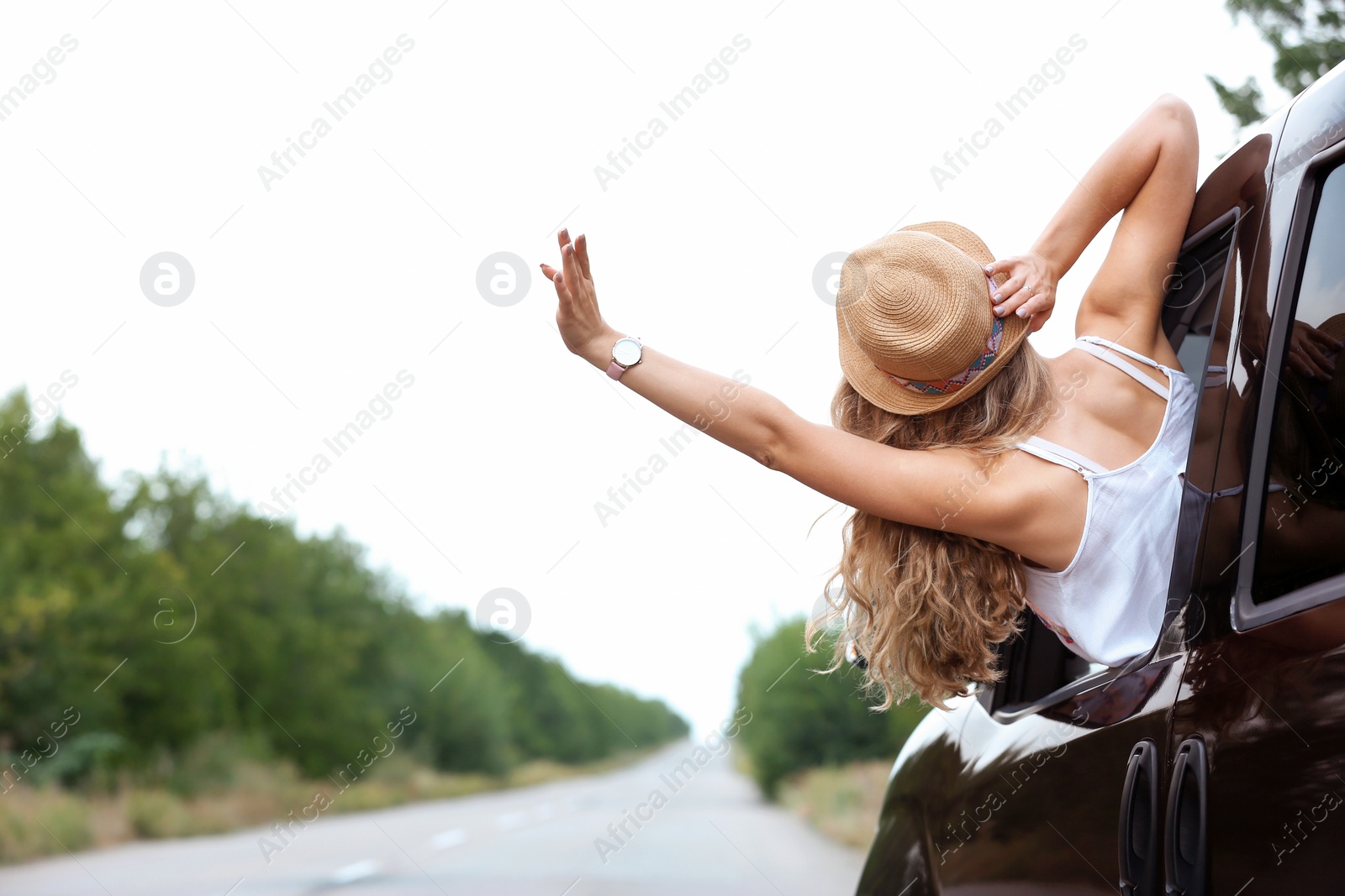 Photo of Happy woman looking out of car window while traveling. Joy in moment