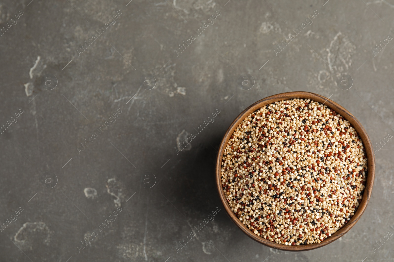 Photo of Bowl with mixed quinoa seeds and space for text on grey background, top view