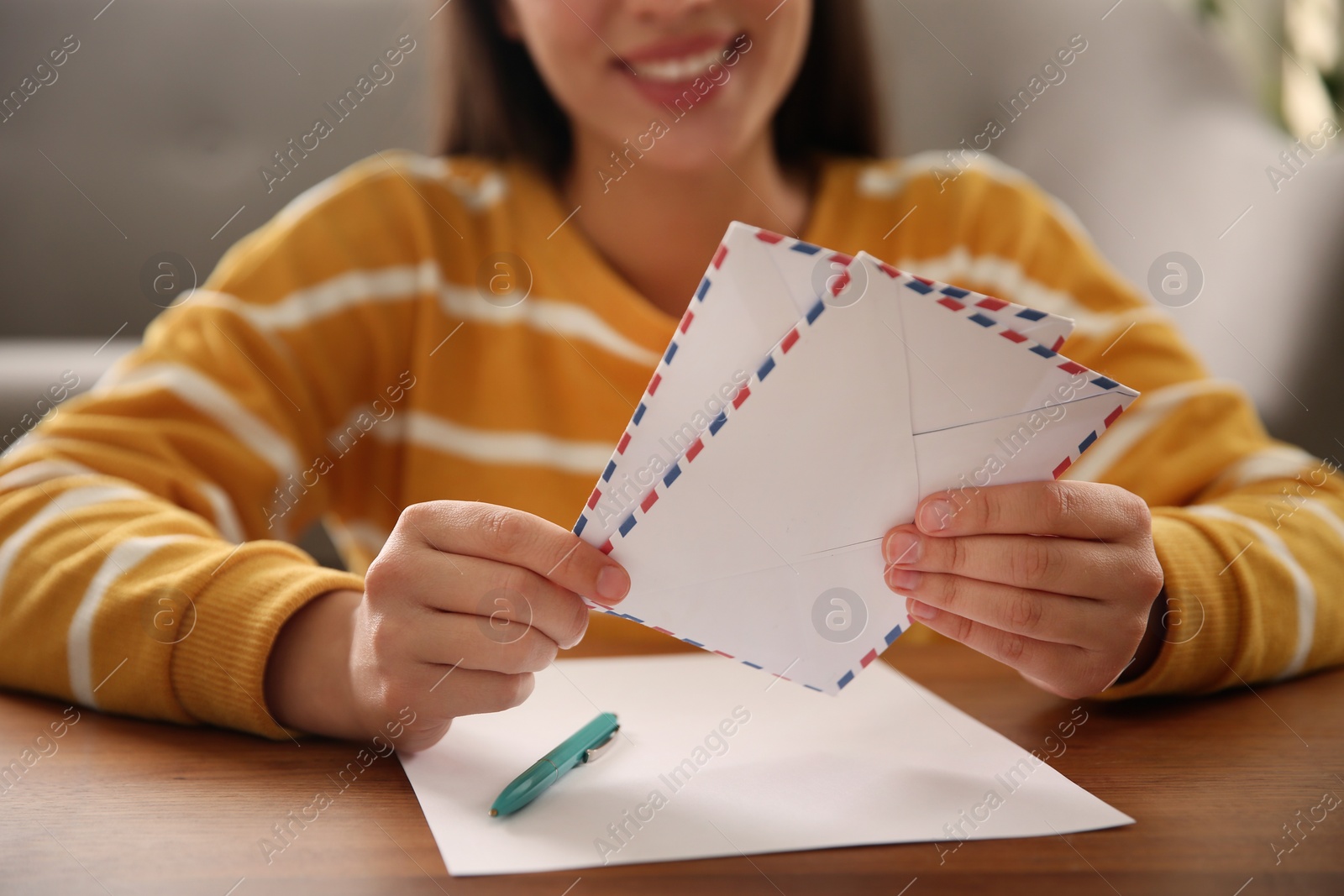 Photo of Woman with letter and envelopes at wooden table indoors, closeup