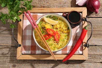 Photo of Stir-fry. Tasty noodles with vegetables and meat in bowl served on wooden table, flat lay