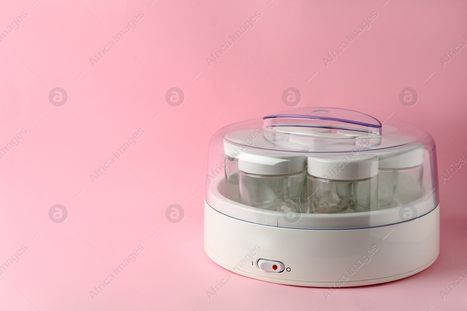 Photo of Modern yogurt maker with empty jars on pink background, space for text