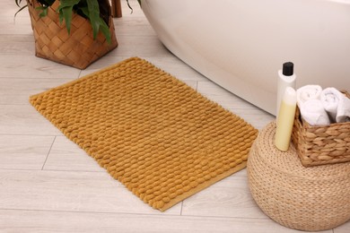 Photo of Soft bath mat, towels and cosmetic products in bathroom