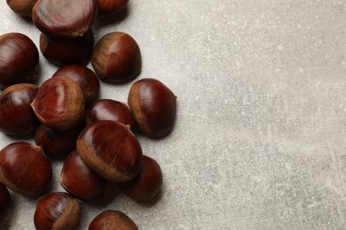 Roasted edible sweet chestnuts on light grey table, flat lay. Space for text