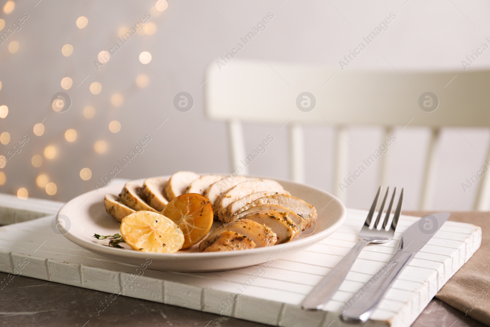 Photo of Tasty lemon chicken served on brown marble table
