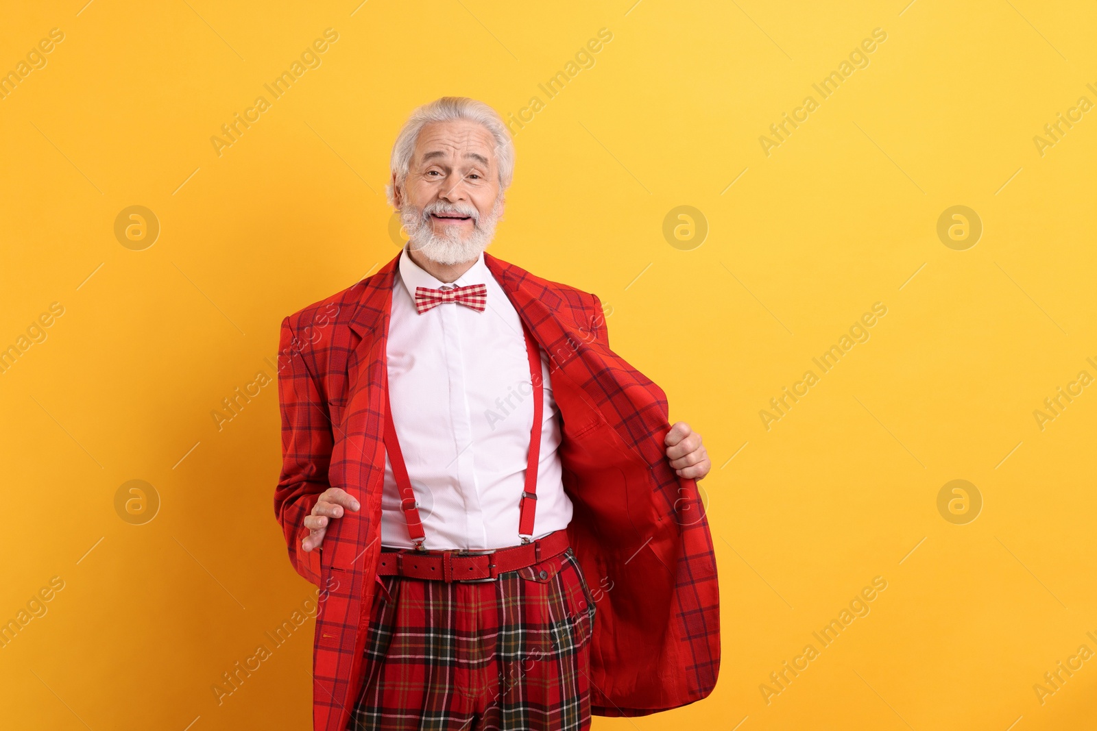 Photo of Portrait of grandpa with stylish red suit and bowtie on yellow background, space for text