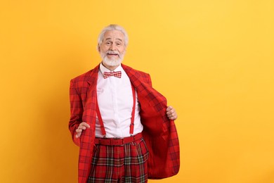 Portrait of grandpa with stylish red suit and bowtie on yellow background, space for text