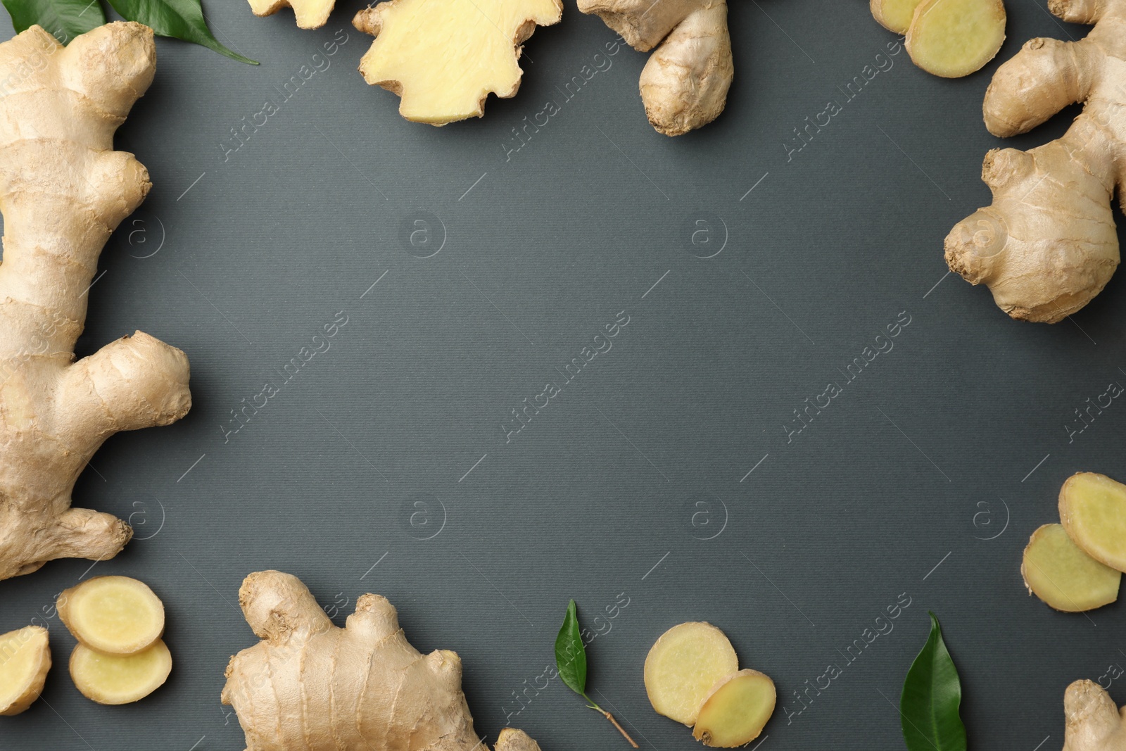 Photo of Frame of fresh ginger with green leaves on dark background, flat lay. Space for text