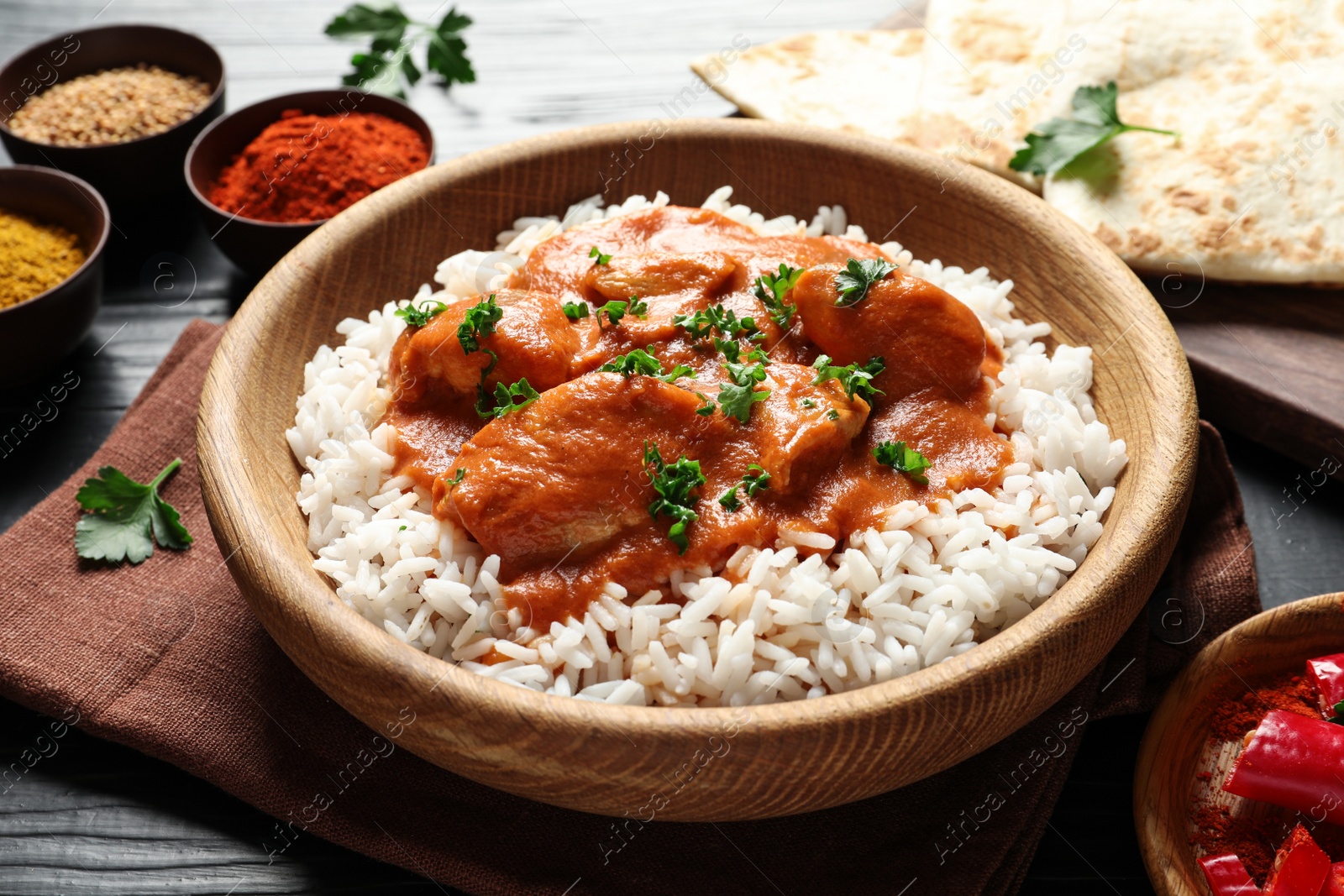 Photo of Bowl of butter chicken with rice on table