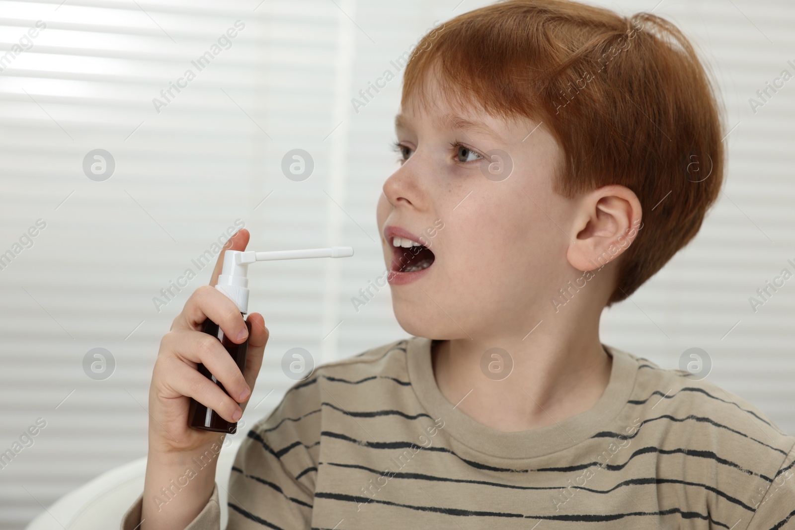 Photo of Little boy using throat spray at home