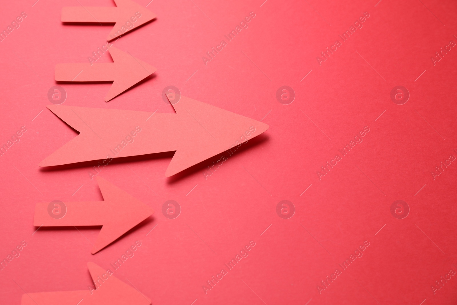 Photo of Many paper arrows on red background, above view. Space for text