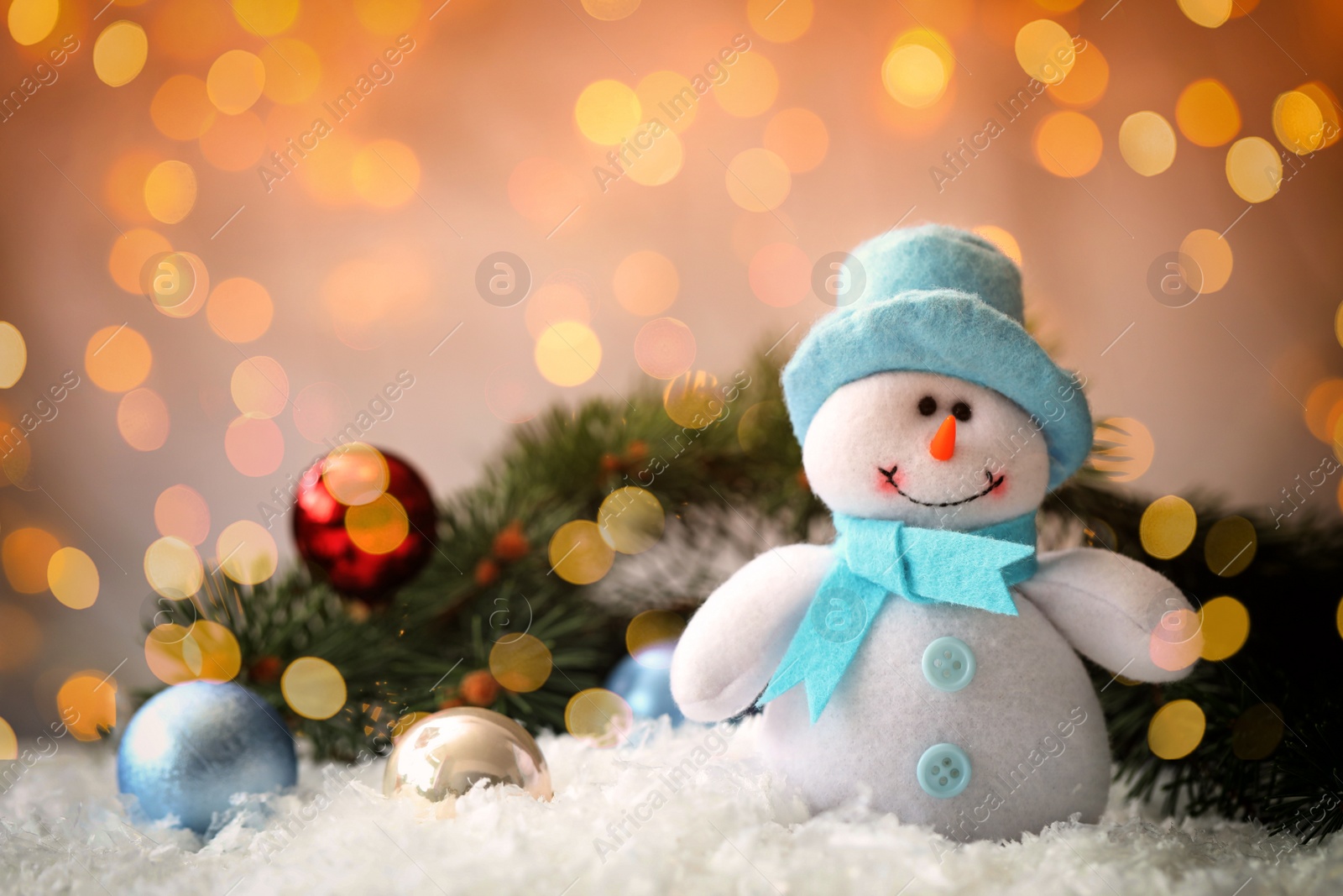 Image of Cute snowman and fir tree branches with Christmas balls on snow, bokeh effect. Space for text