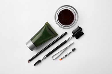Photo of Flat lay composition with eyebrow henna, professional tools and cosmetic product on white background