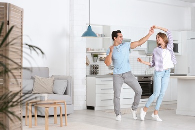 Photo of Beautiful young couple dancing in kitchen at home