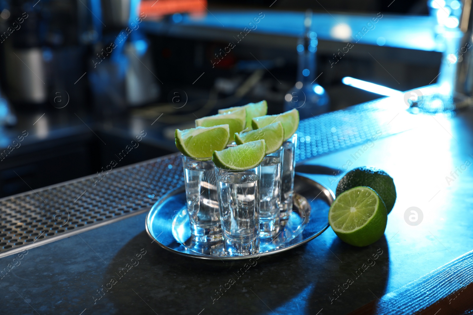 Photo of Mexican Tequila shots with lime slices on bar counter