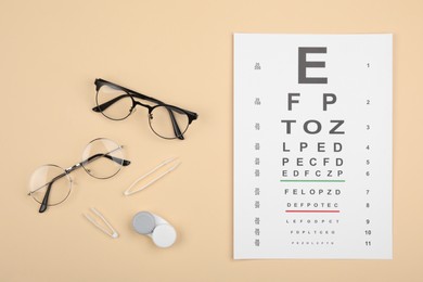 Photo of Vision test chart, glasses, lenses and tweezers on beige background, flat lay