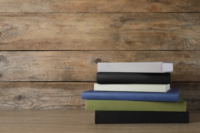 Stack of hardcover books on wooden table, space for text