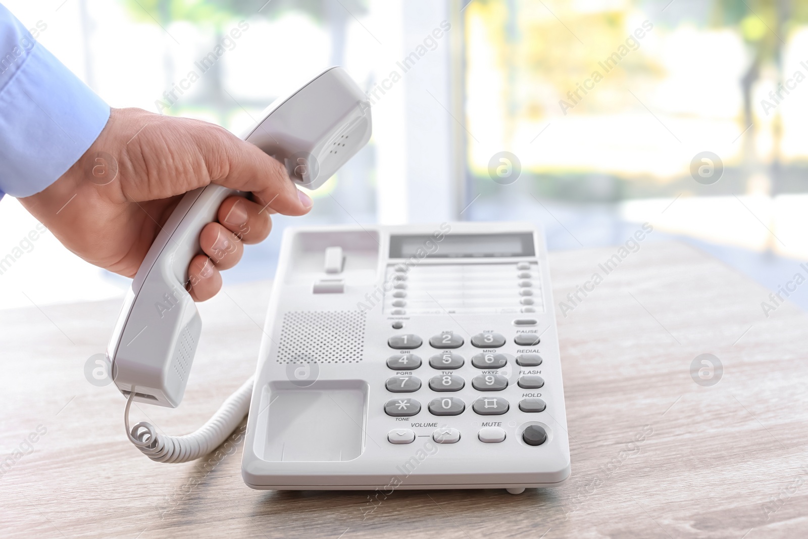 Photo of Man picking up telephone at table indoors