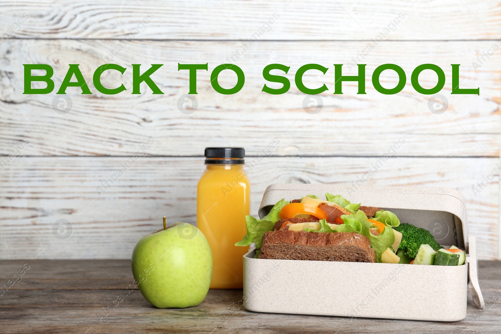 Image of Healthy food for school child in lunch box on table near white wooden wall