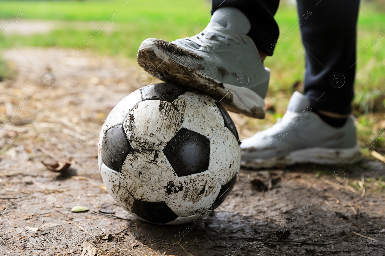 Photo of Man with dirty soccer ball outdoors, closeup