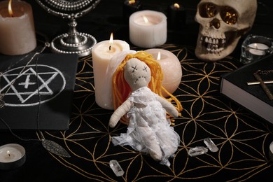 Voodoo doll pierced with pins and candles on black mat. Curse ceremony