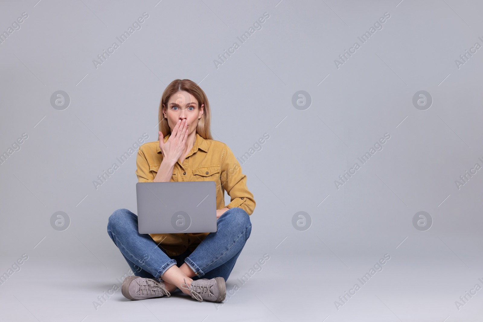Photo of Emotional woman with laptop on light grey background. Space for text